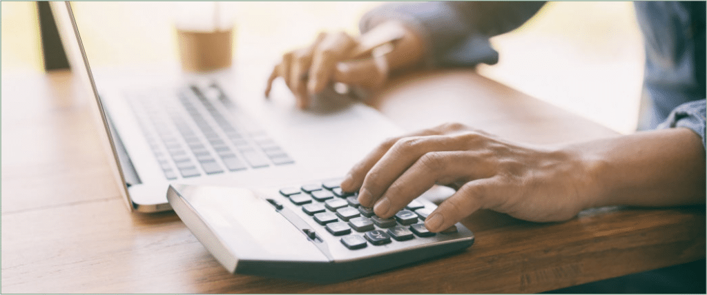 An Image Of Hands On A Calculator And Laptop Keyboard.