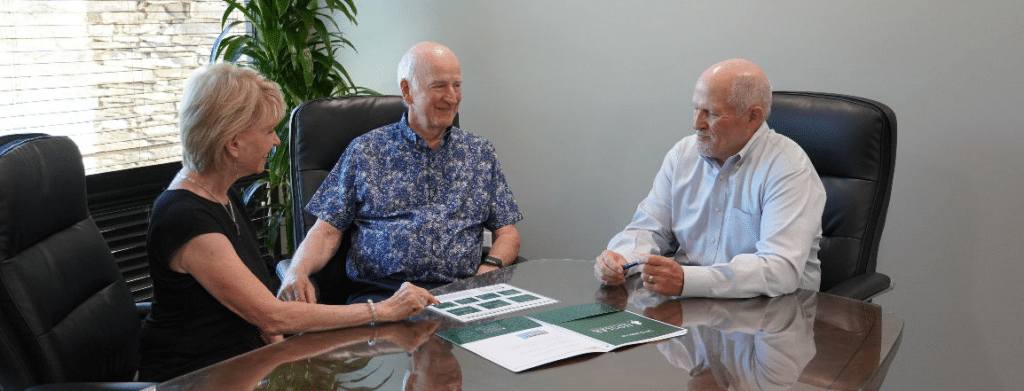 An Image Depicting Two Elderly Individuals Sitting At A Conference Table With A Financial Consultant.